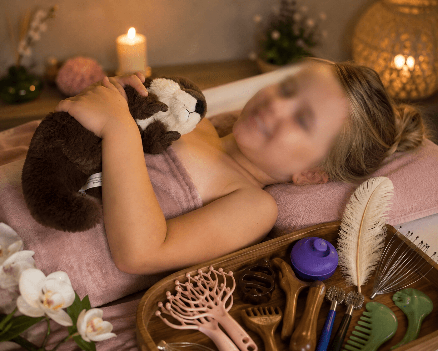 Enfant allongé pendant un head spa, serrant Louna la loutre, à côté du plateau d'accessoires